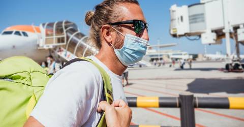 Man bij luchthaven die met vliegtuig reist tijdens pandemie van Coronavirus